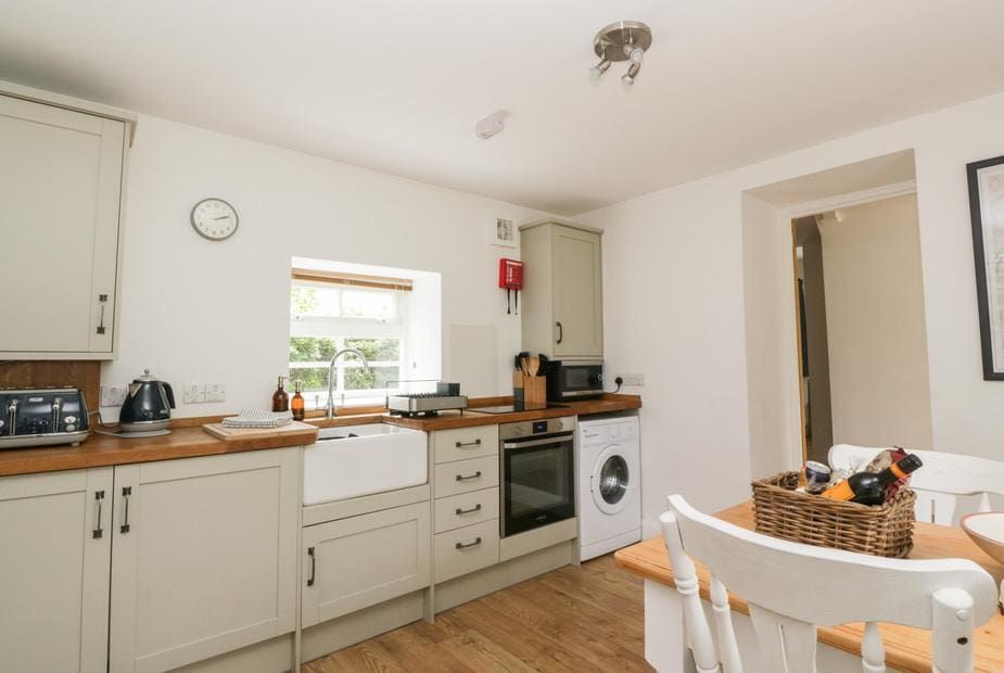 Kitchen with light grey shaker cabinets and Belfast sink at Ellanderroch