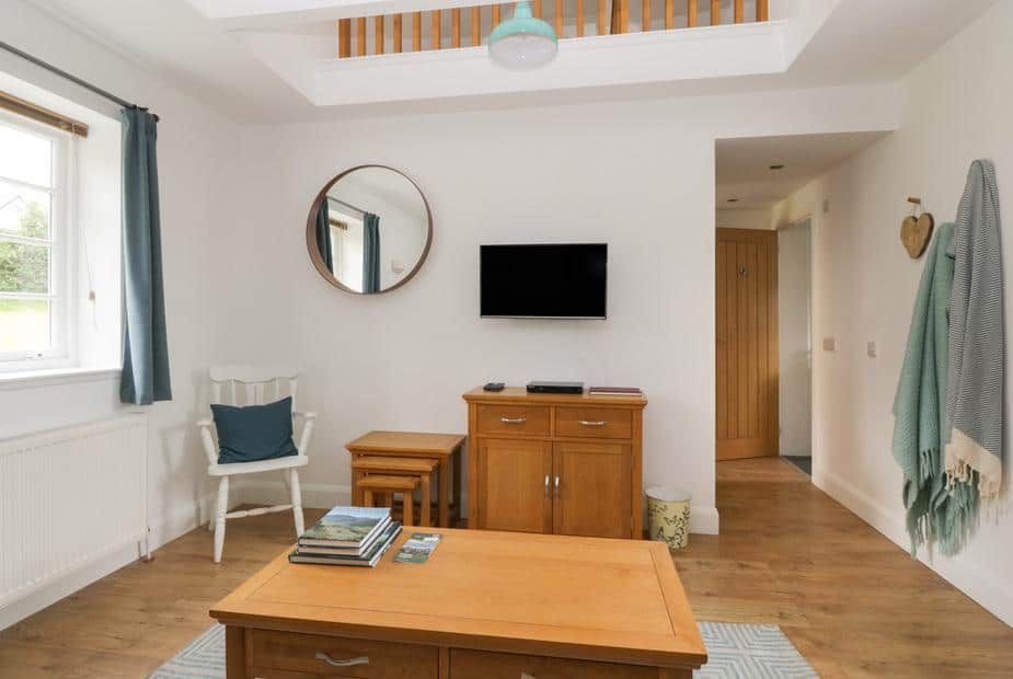 Bright living area with wooden flooring and sideboard at Ellanderroch