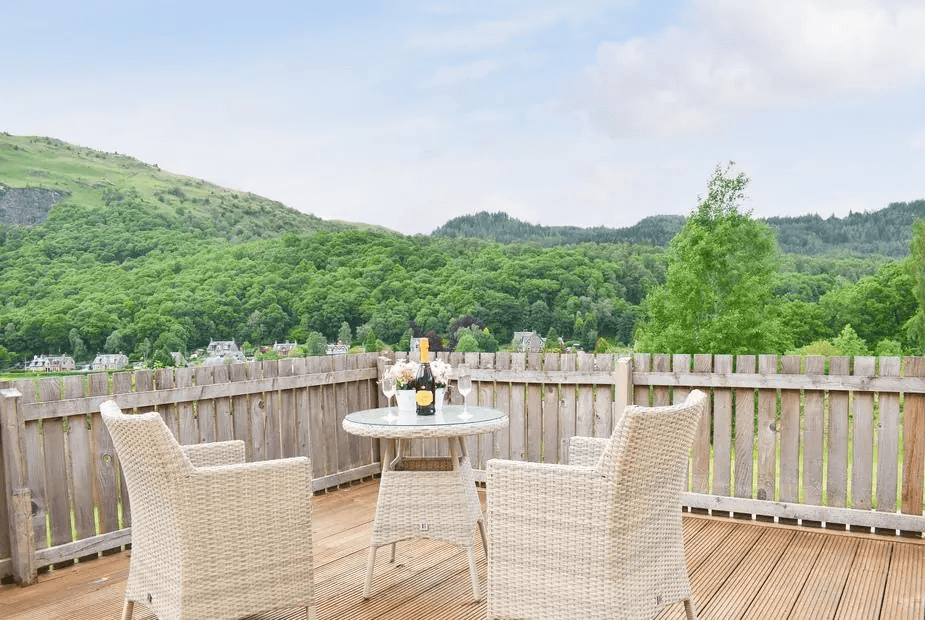 Private balcony with wicker chairs and wine overlooking the valley at Faodail, Aberfoyle