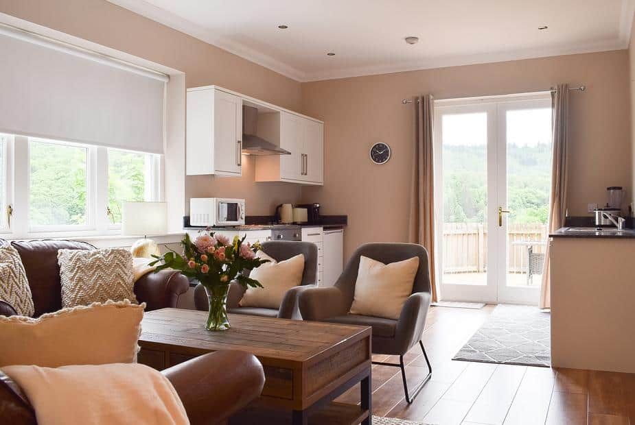 Open-plan living and kitchen area with leather sofas and French doors to balcony at Forth View