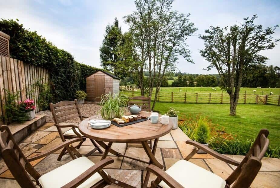 Stone terrace with wooden dining table overlooking the countryside at Gaidrew Cottage