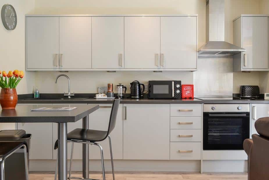 Modern kitchen with white high-gloss cabinets and dark countertops at Hazel Apartment