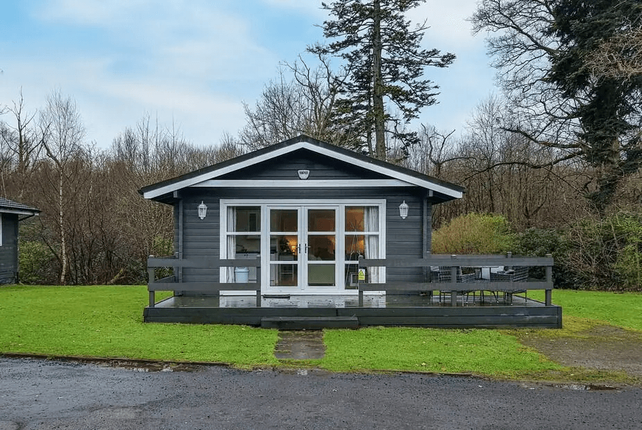 Dark grey wooden lodge with front deck and large glass doors at Leven Lodge 3, Alexandria