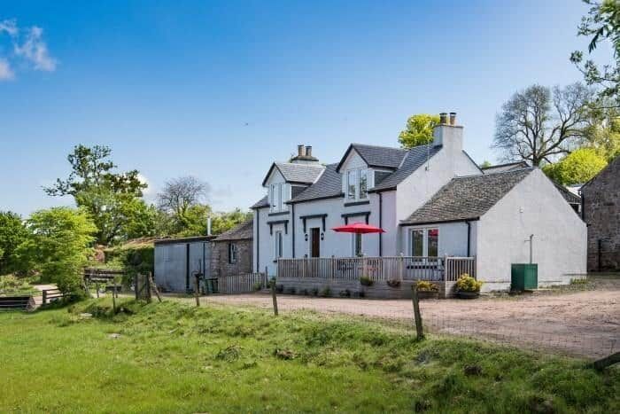 The Old Farmhouse white two-storey cottage with wooden deck and red parasol, Balloch