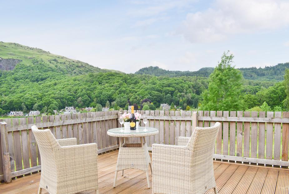 Private balcony with wicker chairs and wine overlooking the valley at Faodail, Aberfoyle