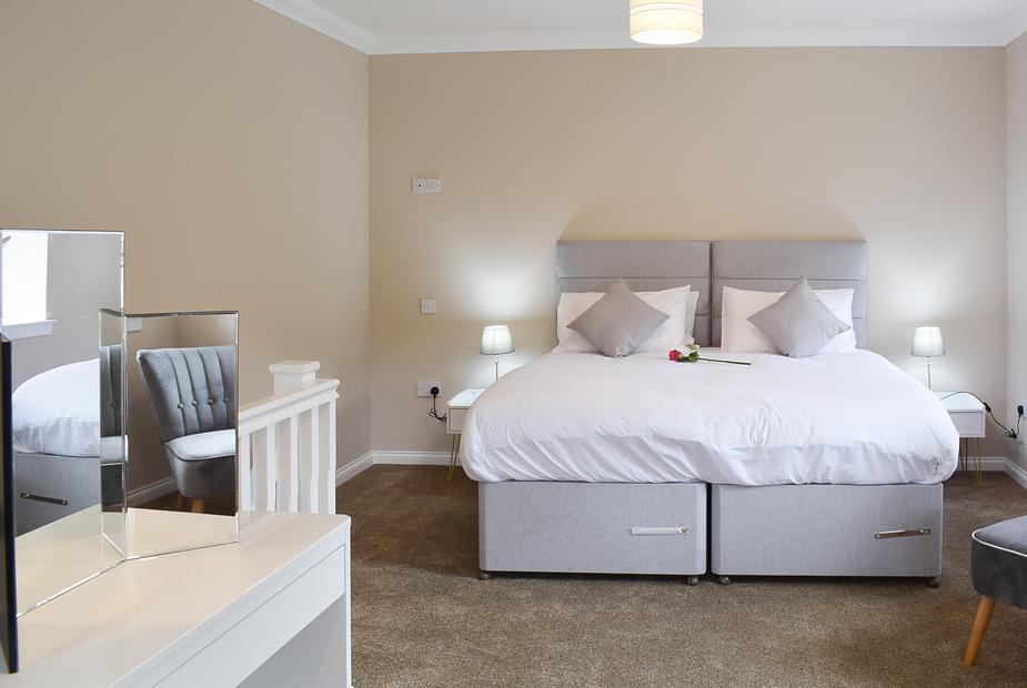 Double bedroom with plush grey headboard and soft bedside lighting at Faodail
