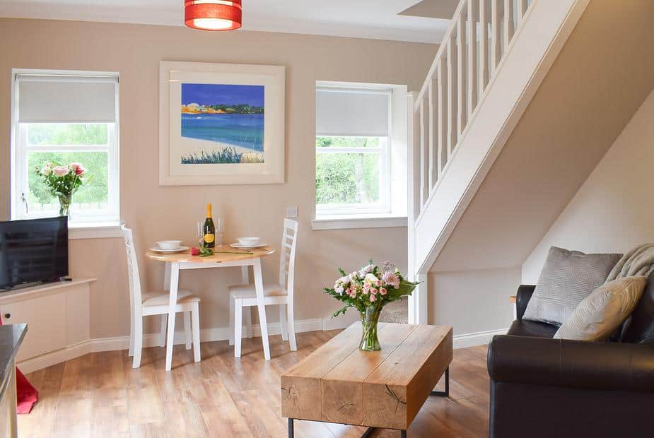 Bright dining area with minimalist white table and staircase at Faodail
