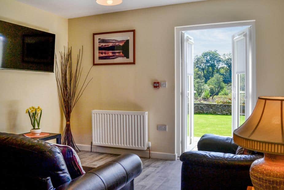 Hazel Apartment living area with leather seating and glass doors opening to garden
