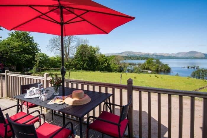 Outdoor dining on the deck with views across fields to Loch Lomond at The Old Farmhouse