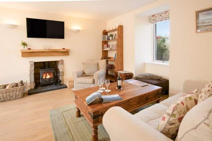 Living room with stone fireplace and wood-burning stove at The Old Farmhouse