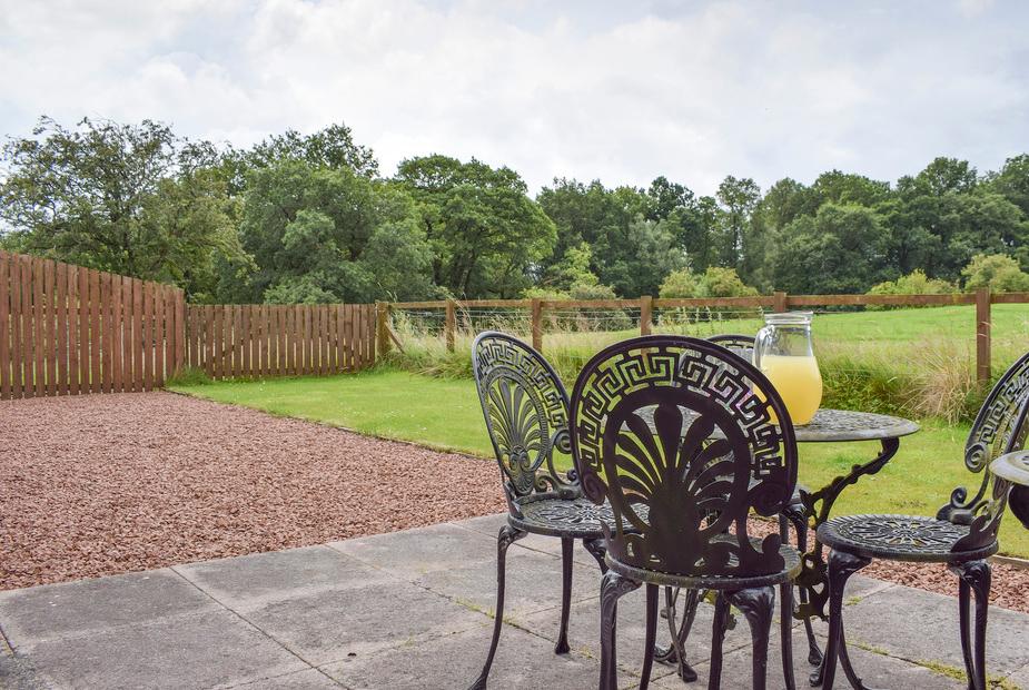 Ornate metal patio furniture overlooking open green fields at The Stables